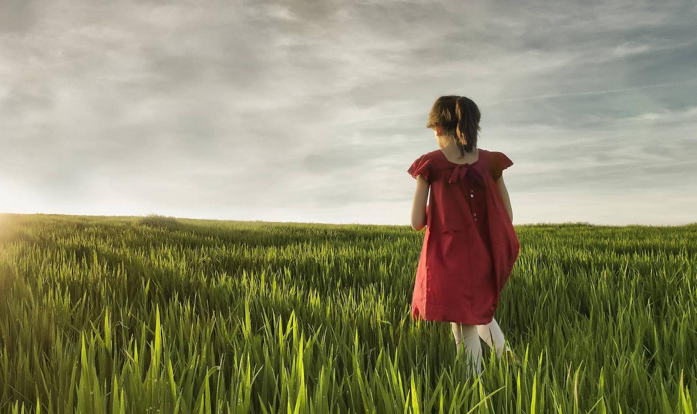 Niña con vestido rojo en un campo verde